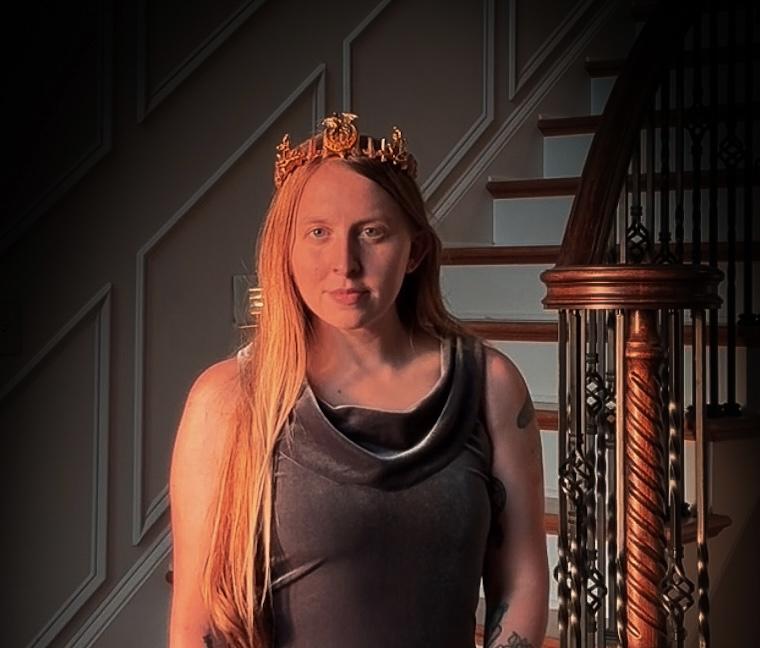 Ashley wearing a crown, lit by warm light