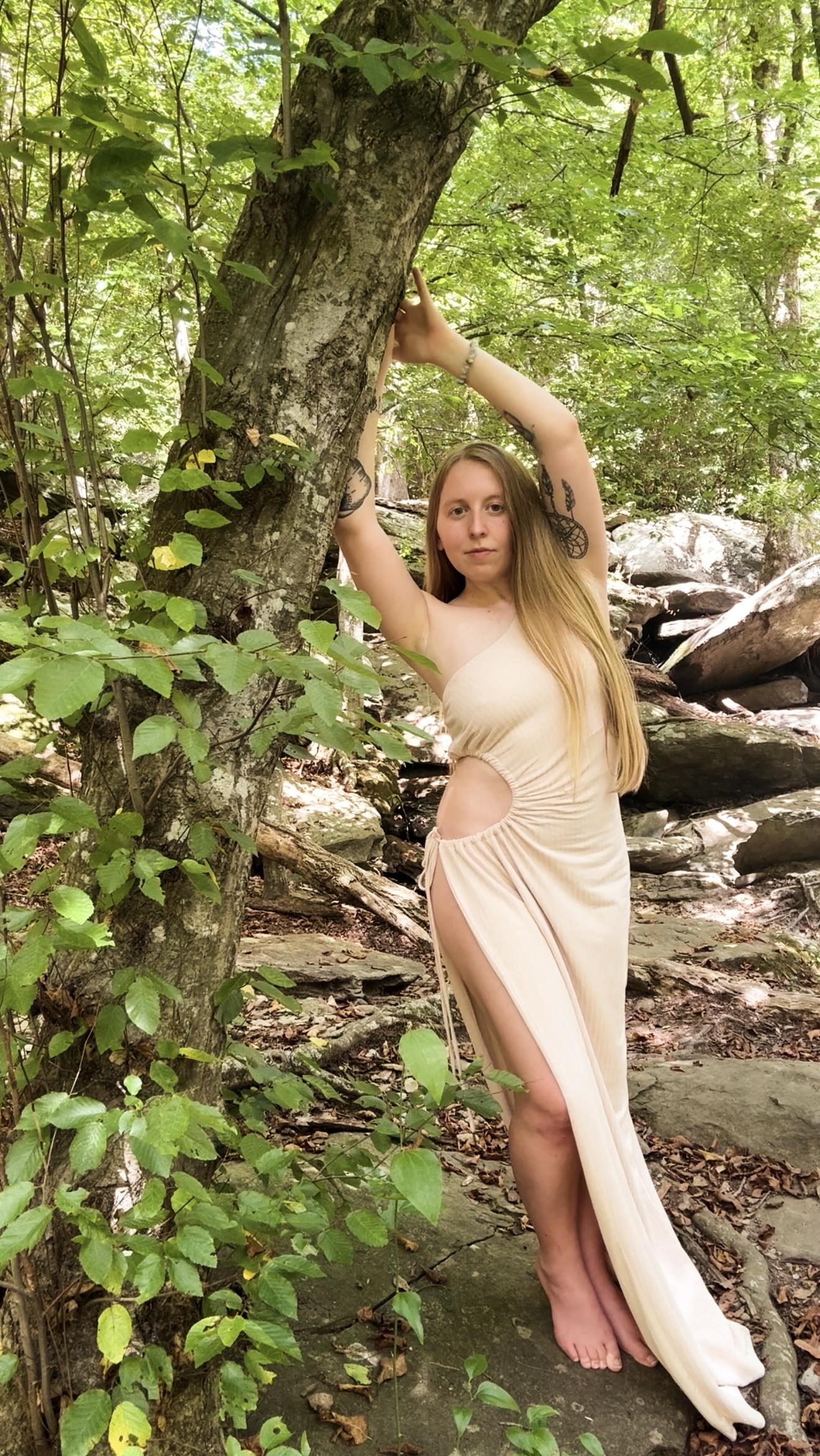 Ashley standing beside a tree in the woods