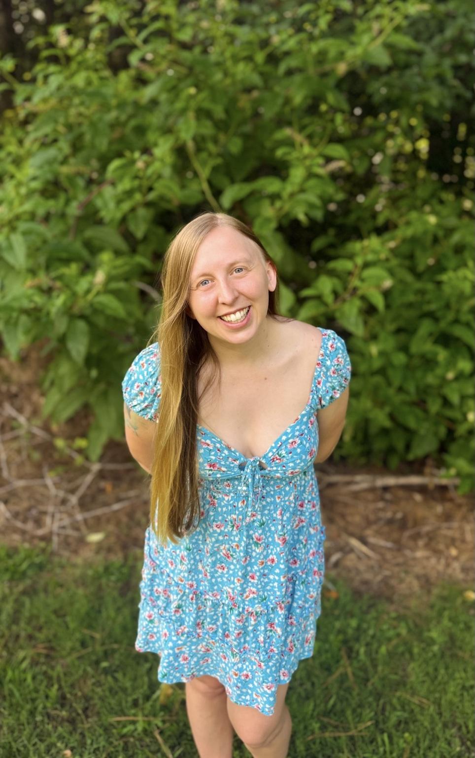 Ashley Clair smiling outdoors in a blue dress